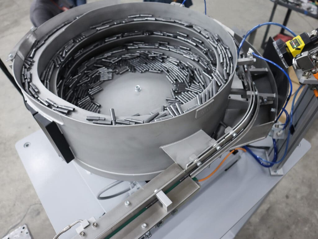 Properly oriented bolt blanks are released into the tooled belt conveyor powered by an end drive motor.