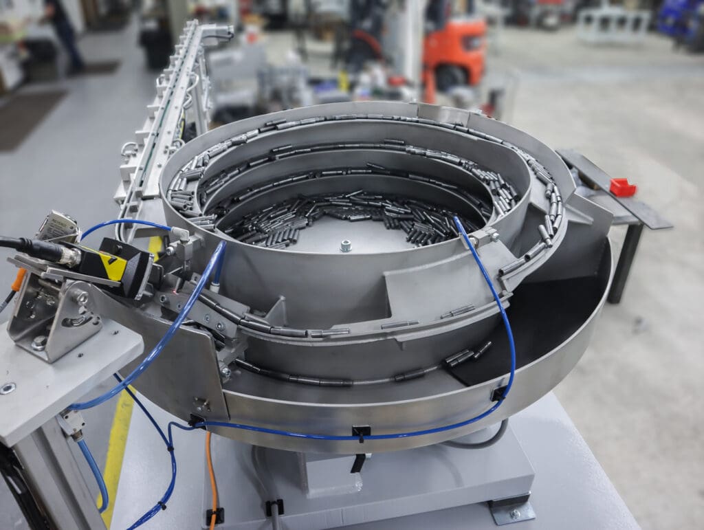 Properly oriented bolt blanks are released into the tooled belt conveyor powered by an end drive motor.