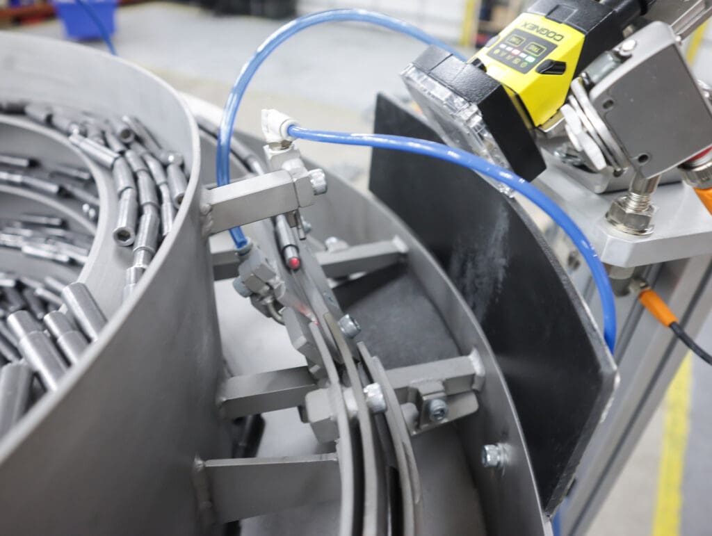 Vision system verifies that each bolt blank is in the required position before discharging the bolt into the vibratory bowl for recirculation.